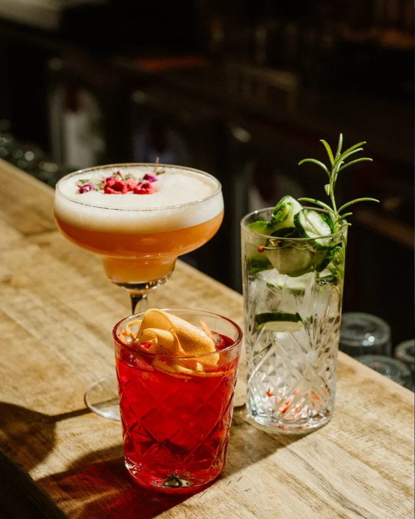 Two drinks on a wooden table with soft, cinematic lighting and lounge background