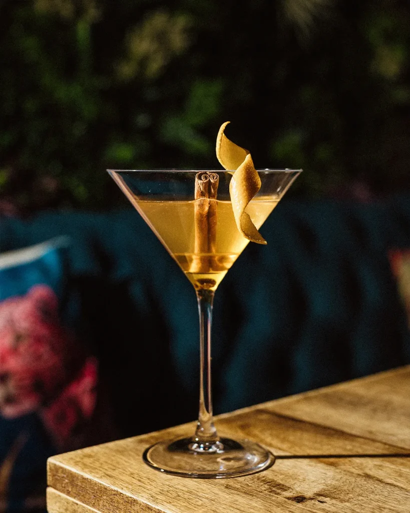 Two martini-style cocktail glasses on a wooden table, elegant evening atmosphere