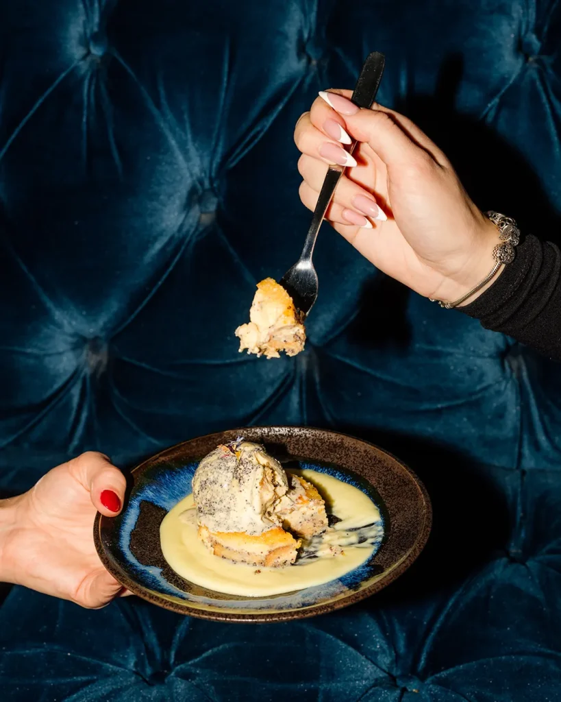 Spoon lifting a bite from a plated dessert, warm low-light dining mood