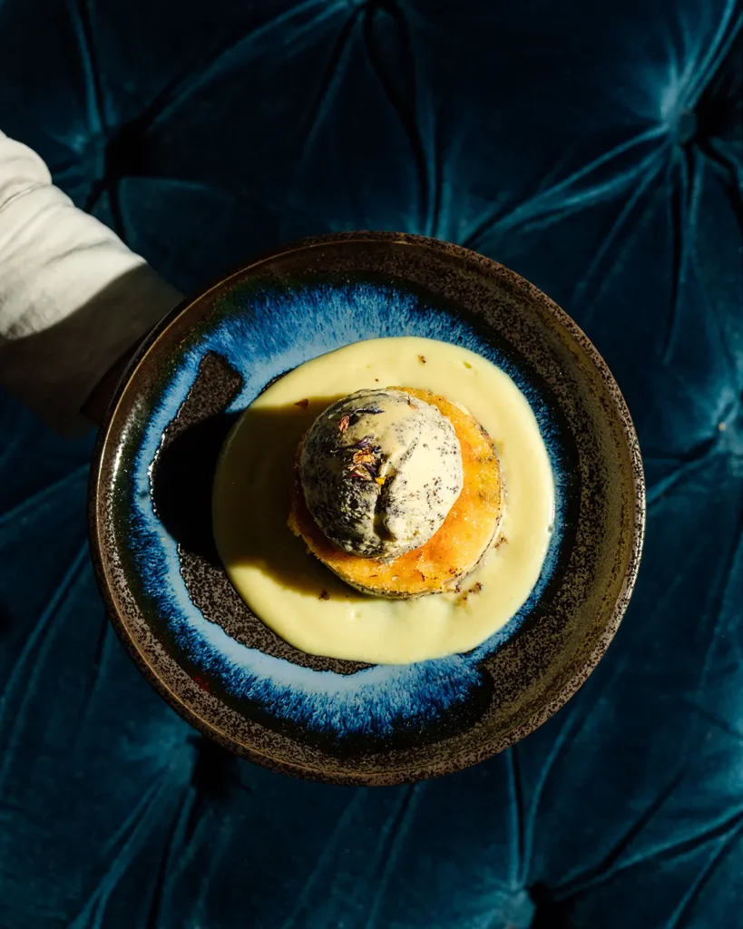Close-up of a dessert in a bowl with rich textures, set on a dark table in lounge lighting