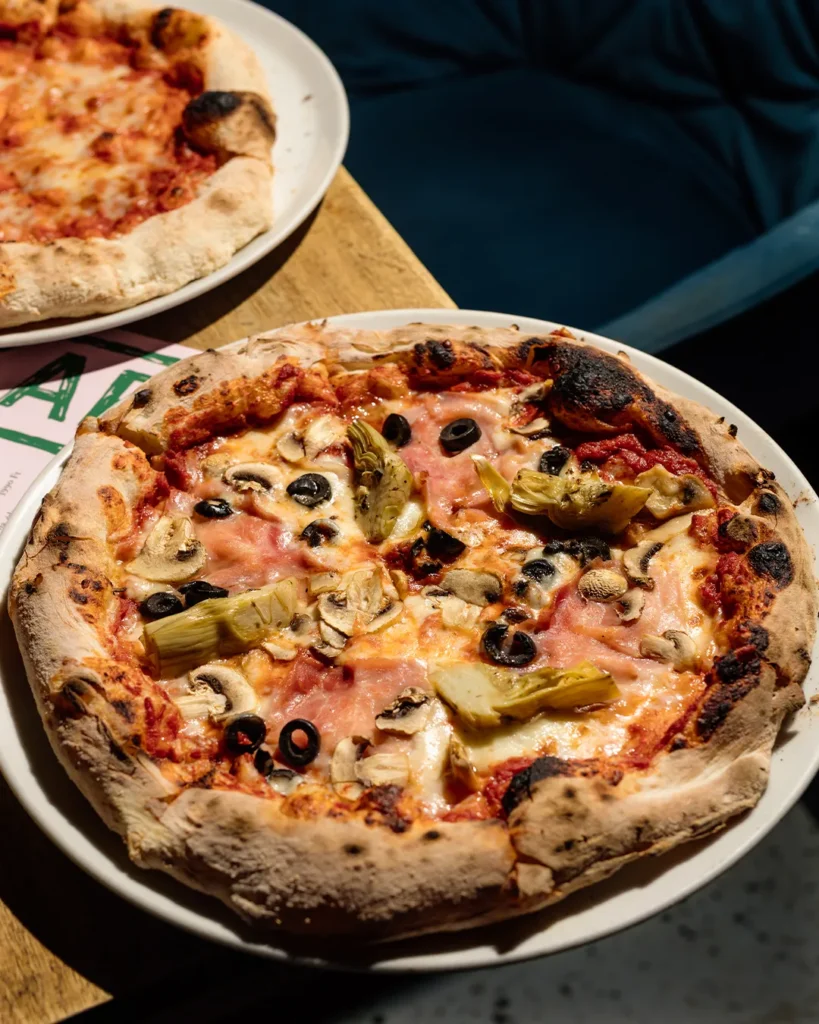Whole pizza on a table with warm lighting and dark lounge background