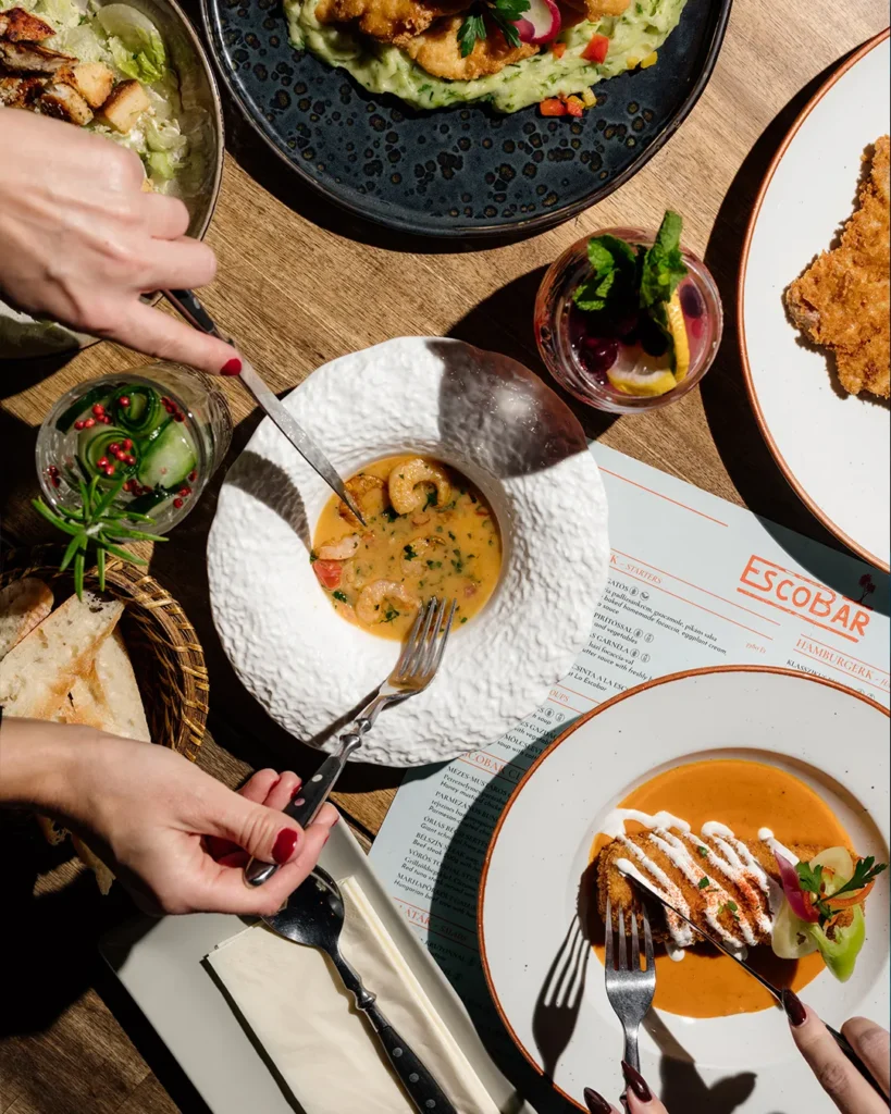 Overhead view of multiple dishes on a table, hands serving and sharing food